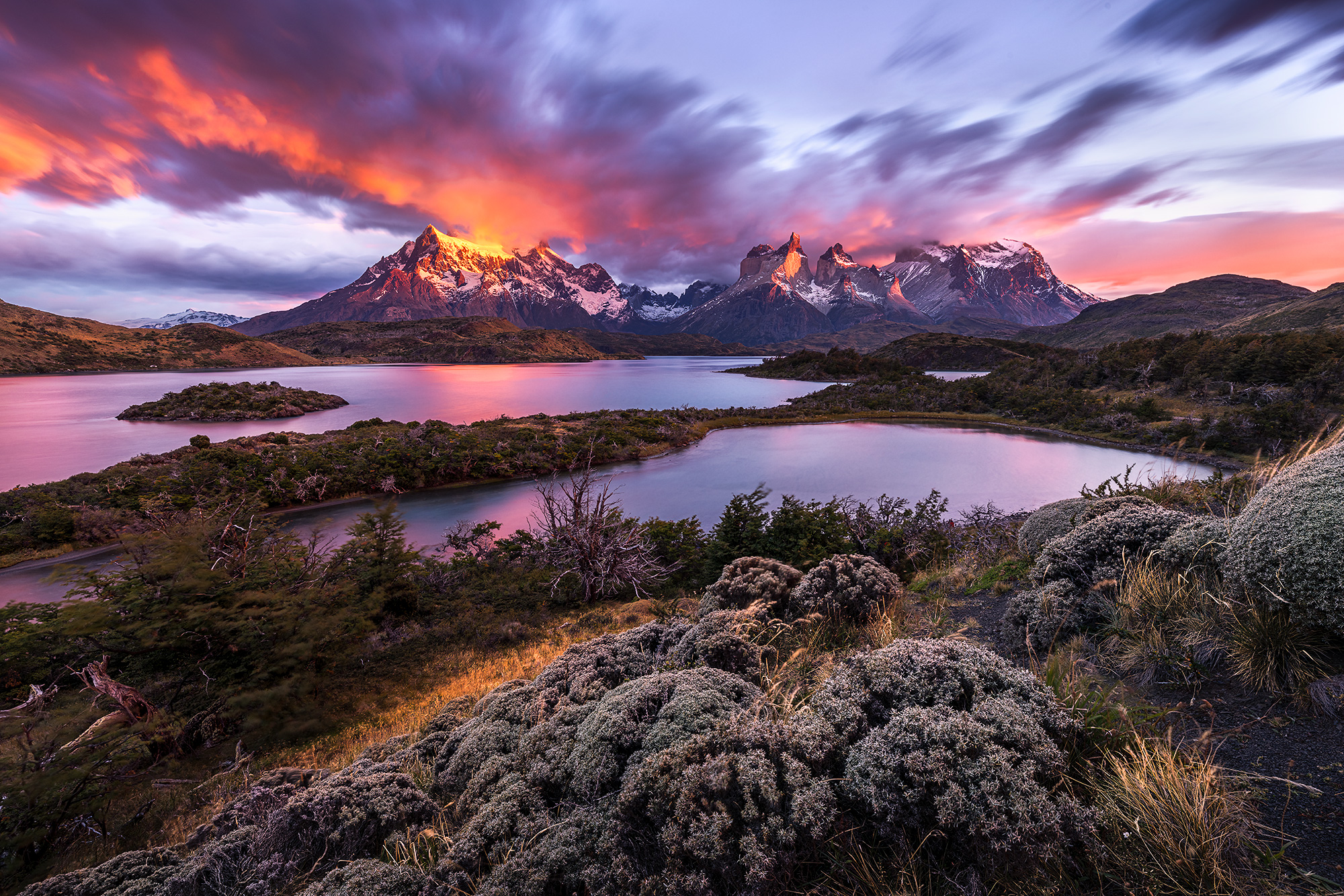 Aflame Sunrise lights up the peaks of Torres del Paine above the lakes of Patagonia
